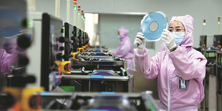 A staff member works on the production line of a semiconductor manufacturer in Binzhou, Shandong province. [Photo by Chu Baorui/For China Daily]
