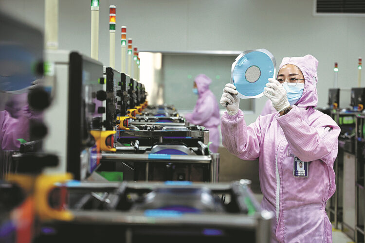 A staff member works on the production line of a semiconductor manufacturer in Binzhou, Shandong province. [Photo by Chu Baorui/For China Daily]