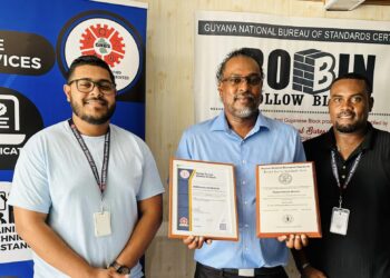 Owner of Robin Hollow Blocks Mr. Raphael Singh and GNBS Technical Officer Mr. Keon Rankin affixed a Certification sticker to the block making equipment