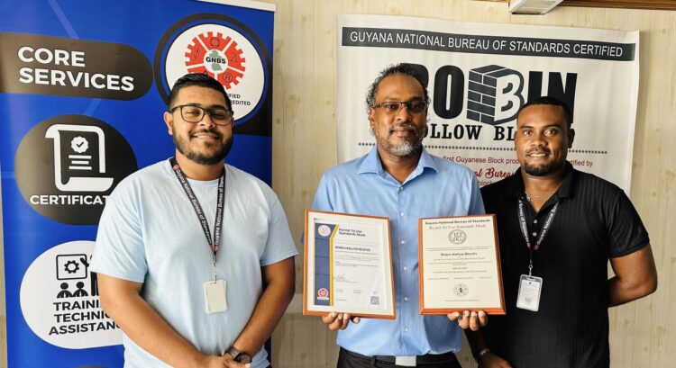 Owner of Robin Hollow Blocks Mr. Raphael Singh and GNBS Technical Officer Mr. Keon Rankin affixed a Certification sticker to the block making equipment