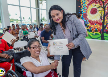 Minister of Human Services and Social Security, Honorable Dr. Vindhya Persaud (right) hands over to Hannah Joseph her certificate