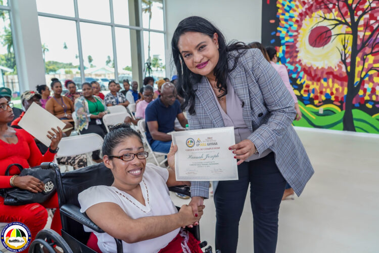 Minister of Human Services and Social Security, Honorable Dr. Vindhya Persaud (right) hands over to Hannah Joseph her certificate
