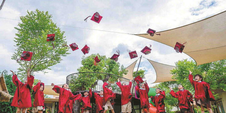 Primary school students, including Gu Keyu's daughter, fourth right, celebrate the end of the summer term in Chiang Mai, Thailand, in June 2019. [Photo/China Daily]