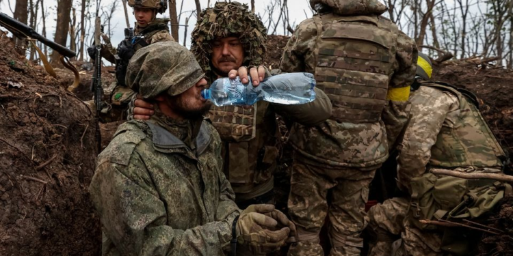 A Ukrainian soldier gives water to a captured Russian army serviceman, according to them, on a position recently gained in offensive, as Russia's attack on Ukraine continues, near the front line city of Bakhmut, in Donetsk region, Ukraine May 11, 2023. Radio Free Europe/Radio Liberty/Serhii Nuzhnenko via REUTERS