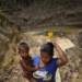  An Amerindian woman carries her child after bathing him in a river, in Chinese Landing, Guyana, Monday, April 17, 2023. Descendants of Caribs, the Amerindians living in Chinese Landing have seen their land shrink as miners scrape back layers of rock and red soil. (AP Photo/Matias Delacroix)