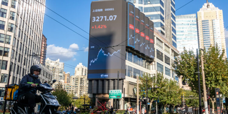 A deliveryman rides past an electronic board in West Nanjing Road in Jing'an district, Shanghai, displaying the trading day's closing levels of key indexes of the Shanghai Stock Exchange and the Shenzhen Stock Exchange on Nov 3. [WANG GANG/FOR CHINA DAILY]