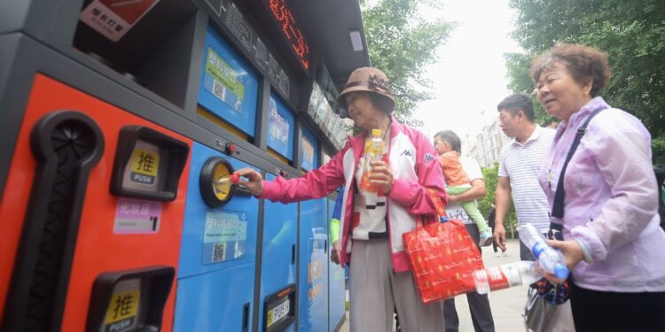 Residents throw plastic bottles in a trash bin with detailed sorting instructions in Beijing. [Phtot by Wei Tong/For China Daily]