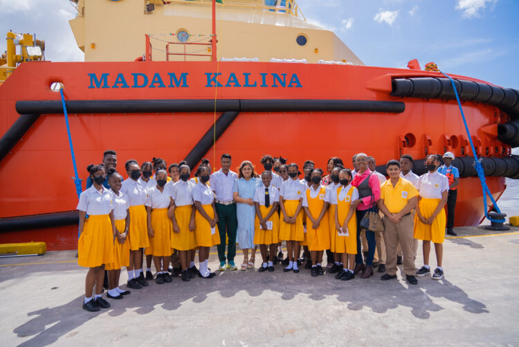 Minister of Education, Priya Manickchand taking a photograph with students of the Brickdam Secondary School including Kaylan Duncan as well as Raymond De Cambra of the St. Ignatius Secondary School in front of the Madam Kalina which was named by Kaylan