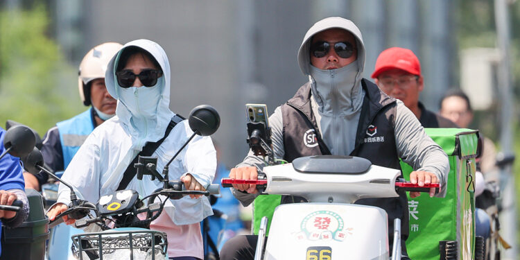 Passengers wear sun-protective clothing in Beijing, June 23, 2023. /CFP