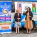 Minister of Human Services and Social Security, Dr. Vindhya Persaud (right) collects the keys to the 17-seat bus from U.S. Ambassador to Guyana Sarah-Ann Lynch