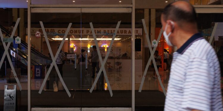 A man walks past a shopping mall with masking tape in the Tsuen Wan district as a precaution for the approaching typhoon Talim in Hong Kong on July 16, 2023. Talim, the fourth typhoon of 2023, is forecast to come ashore in China on the night of July 17, 2023. Photo: VCG