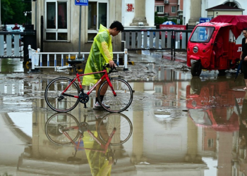 People walk along a water laden street, after heavy rains in Mentougou district in Beijing, China, July 31, 2023. /CFP