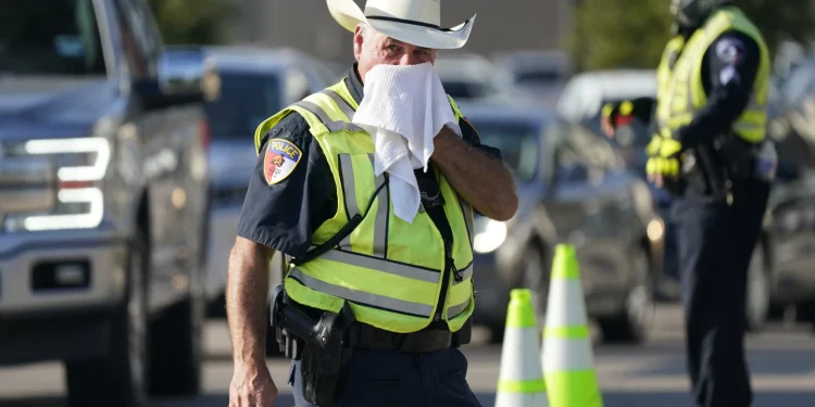 Pollice Officer Rhodes used a wet rag to cool off as he directs traffic in Arlington , Texas on Thursday (AP photo)
