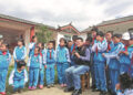 Bian Huawei prepares to take photos of students at Runan Primary School in Yulong Naxi autonomous county, Yunnan province, during a visit. CHINA DAILY
