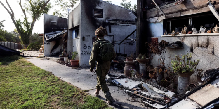 An Israeli soldier walking past destroyed houses in Kibbutz Beeri, Israel, October 2023