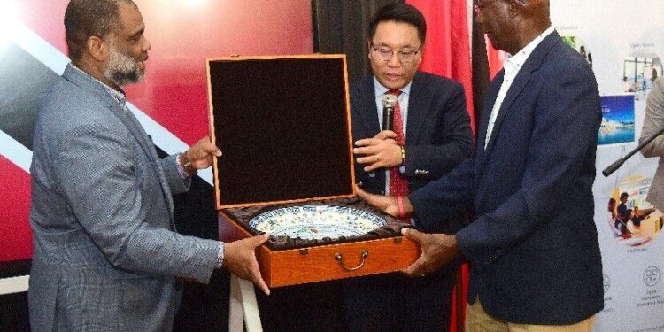 :‘HUGE BENEFITS’: Tudor John, enterprise director for Huawei T&T, and Daniel Zhou, president of Huawei Technologies Latin America, present Prime Minister Dr Keith Rowley with a traditional Chinese gift yesterday following the donation of a Huawei Ideahub Digital Board and 50 tablets to the Carenage Police Youth Club and Homework Centre, Carenage. —Photo: JERMAINE CRUICKSHANK