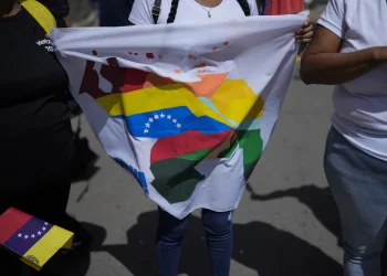 A woman holds a flag during a voting rehearsal for the upcoming December referendum for the territorial dispute between Venezuela and Guyana in Caracas Venezuela Saturday November 19, 2023 (AP Photo/ Ariana Cubillos)
