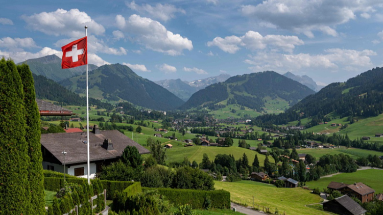 A Swiss flag and the Alps surrounding the resort of Gstaad in Saanen municipality, July 23, 2023. /CFP