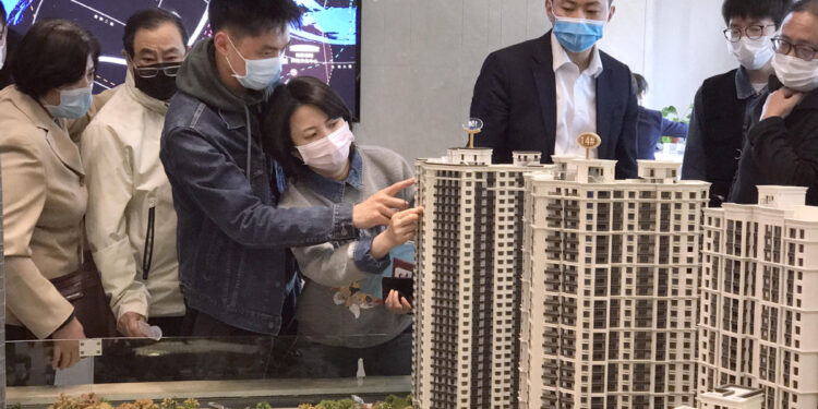 Potential homebuyers check models of housing projects at a real estate agency in Shanghai. [WANG RONGJIANG/FOR CHINA DAILY]