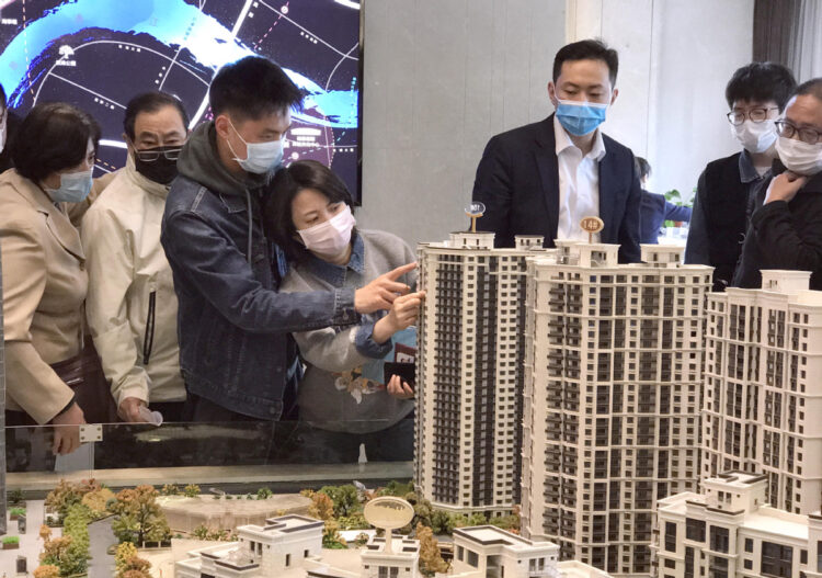 Potential homebuyers check models of housing projects at a real estate agency in Shanghai. [WANG RONGJIANG/FOR CHINA DAILY]