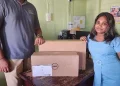 A representative from one of the Neighbourhood Democratic Council (NDC) collecting a computer from a representative from the Ministry of Local Government and Regional Development