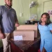 A representative from one of the Neighbourhood Democratic Council (NDC) collecting a computer from a representative from the Ministry of Local Government and Regional Development
