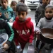 Children with empty pots wait as aid workers distribute food in Gaza City earlier this month