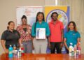 Dunae Trading Company Inc., Chief of Operations, Melissa Younge poses with the MIG Certificate accompanied by her staff