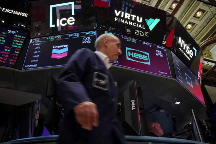Traders work on the floor as screens display the logo for Chevron Corp. and Hess Corp. at the New York Stock Exchange (NYSE) in New York City, U.S., October 23, 2023. REUTERS/Brendan McDermid/File Photo Purchase Licensing Rights
