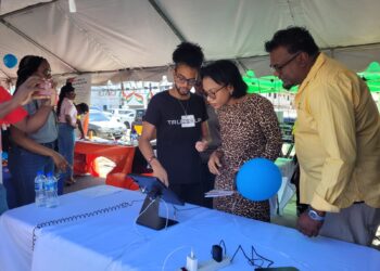 Minister Walrond and Director of CCAC Rabindra Kandhi experiencing communication with the AI Agent at the Expo.