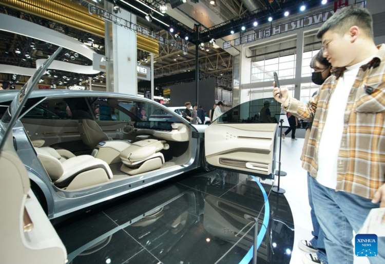People watch a vehicle at the booth of Skyworth Auto at the 2024 Beijing International Automotive Exhibition in Beijing, China, April 30, 2024.