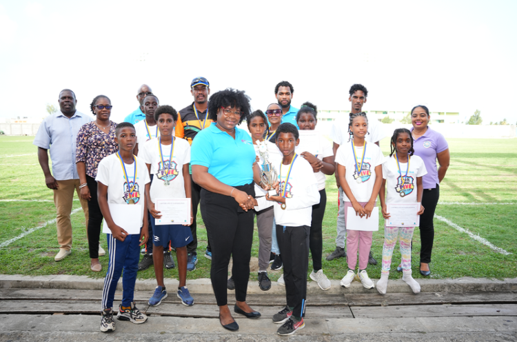 Zaleel Thomas of River Doree Anglican Combined School receives trophy from Florence Demacque, RBEC Vieux Fort- Branch Manager, also in the photo, Director of Sports Clivus Jules, Principal Secretary of the SLNCA Jacqueline Inglis and coaches from Zone 5