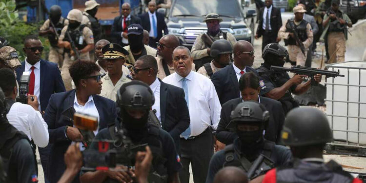 Haitian Prime Minister Garry Conille, center, and Police Chief Normil Rameau, center left, are surrounded by security as they arrive to the General Hospital in Port-au-Prince, Haiti, Tuesday, July 9, 2024. Authorities announced that police took control of the medical institution over the weekend from armed gangs. (AP Photo/Odelyn Joseph)