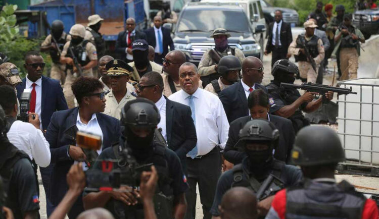 Haitian Prime Minister Garry Conille, center, and Police Chief Normil Rameau, center left, are surrounded by security as they arrive to the General Hospital in Port-au-Prince, Haiti, Tuesday, July 9, 2024. Authorities announced that police took control of the medical institution over the weekend from armed gangs. (AP Photo/Odelyn Joseph)