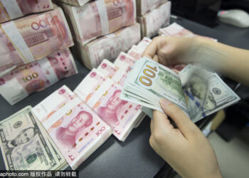 A bank staff member counts RMB and US dollar notes in Nantong, Jiangsu province. [Photo/Sipa]