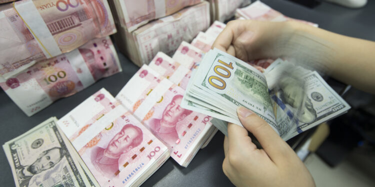A bank staff member counts RMB and US dollar notes in Nantong, Jiangsu province. [Photo/Sipa]