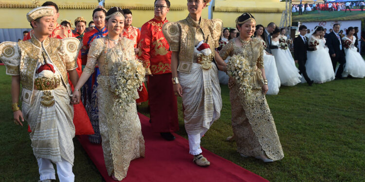 Chinese couples take part in a mass wedding jointly organized by Sri Lankan authorities and the Chinese embassy in the capital of Colombo on Dec 17. Some of the 50 couples wore local traditional clothing for the ceremony in which the hosts tied their little fingers together with cotton threads. [Photo/Agencies]