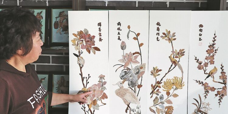 Li introduces her birch bark artworks to tourists in March. CHINA DAILY