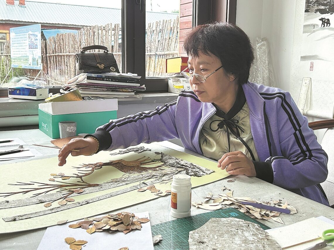 Li introduces her birch bark artworks to tourists in March. CHINA DAILY