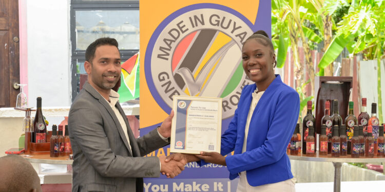 Owner of Propa GT Local Wine, Abigale John receives the GNBS Made in Guyana Certificate from GNBS’ Executive Director, Trevor Bassoo
