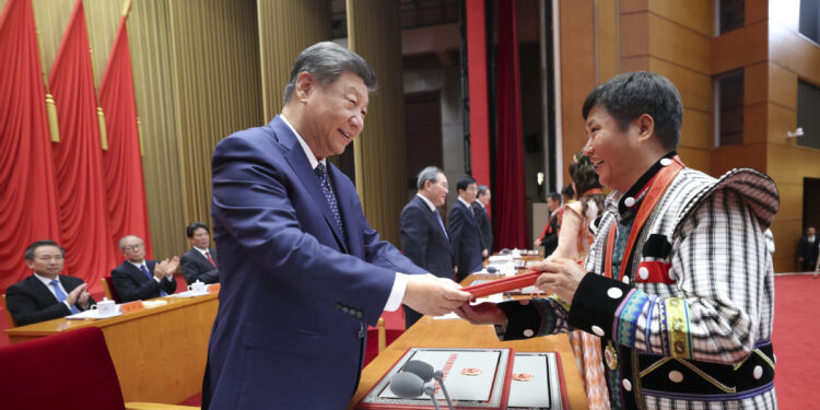 President Xi Jinping presents an award to a role model for ethnic unity and progress at a commendation ceremony in Beijing on Friday. JU PENG/XINHUA