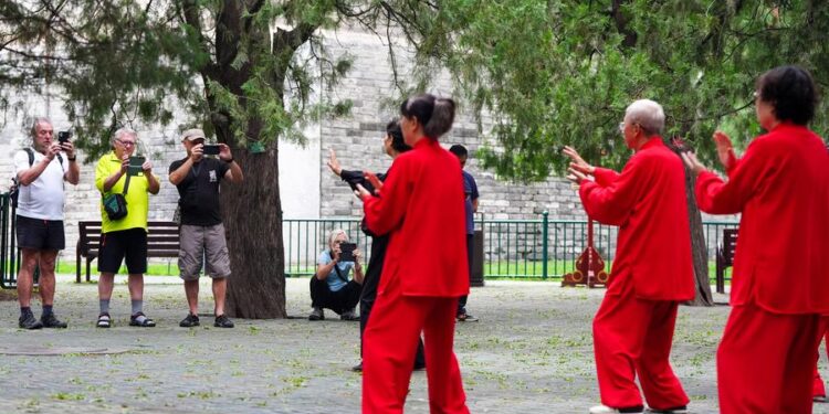 Tourists take photos of citizens practicing Tai Chi at the Tiantan (Temple of Heaven) Park in Beijing, capital of China, July 2, 2024. (Xinhua/Ju Huanzong)