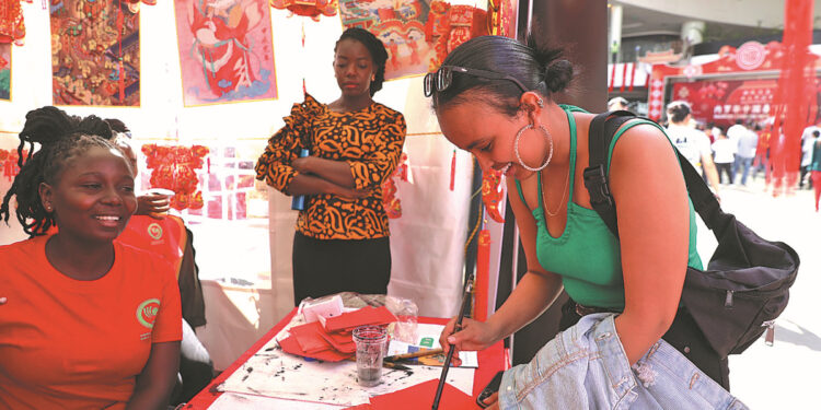 A student from Eritrea learns Chinese calligraphy at a booth set up by the Confucius Institute of Kenyatta University during a Chinese New Year cultural event in Nairobi, Kenya, on Feb 10. WU XIAOHUI/CHINA DAILY
