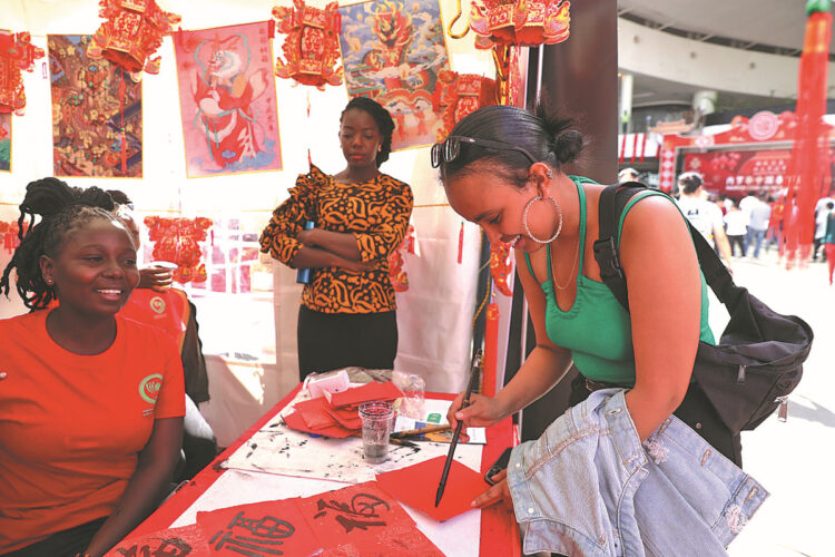 A student from Eritrea learns Chinese calligraphy at a booth set up by the Confucius Institute of Kenyatta University during a Chinese New Year cultural event in Nairobi, Kenya, on Feb 10. WU XIAOHUI/CHINA DAILY