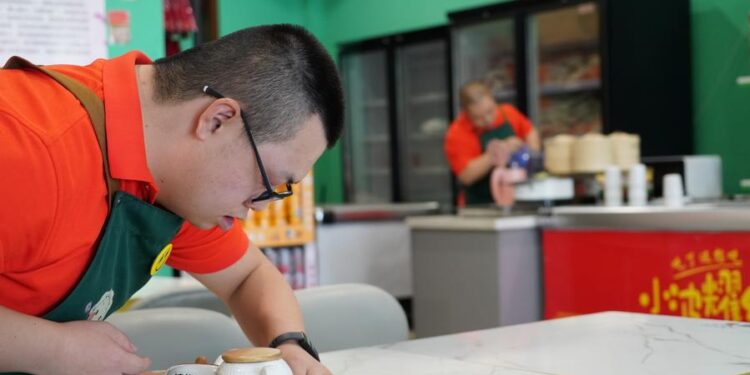Zhang Fan, an employee with Down syndrome, works at Xiaoboyaohong dumpling restaurant in Hohhot, North China's Inner Mongolia autonomous region, Aug 6, 2024. [Photo/Xinhua]