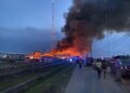 Onlookers watch-on as the warehouse was destroyed by fire on Tuesday afternoon. (Fire completely destroys KN, Bhenas Footwear warehouse leaving hundreds of millions in losses)- Kaieteur News photo