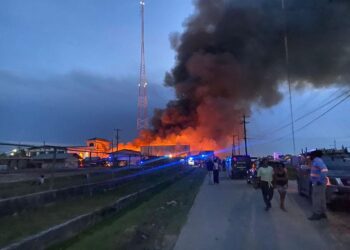 Onlookers watch-on as the warehouse was destroyed by fire on Tuesday afternoon. (Fire completely destroys KN, Bhenas Footwear warehouse leaving hundreds of millions in losses)- Kaieteur News photo