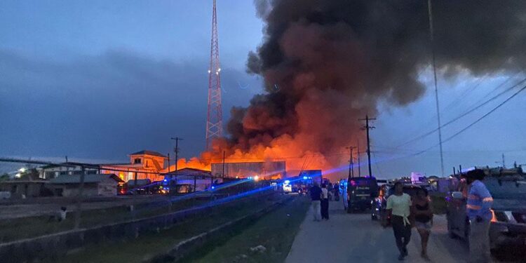 Onlookers watch-on as the warehouse was destroyed by fire on Tuesday afternoon. (Fire completely destroys KN, Bhenas Footwear warehouse leaving hundreds of millions in losses)- Kaieteur News photo
