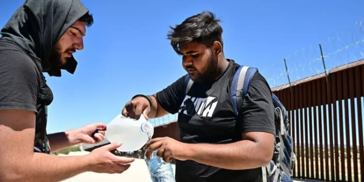 Migrants from India share water in the intense heat after walking into the US from Mexico in June