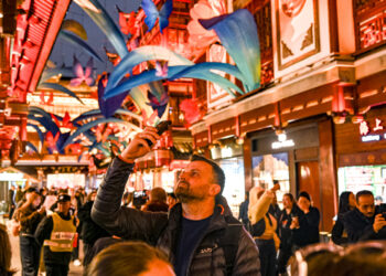 A traveler from Poland takes photos at the Yuyuan shopping center in Shanghai on Dec 4. China's visa-free policies, along with optimized payment options and other visitor-friendly services, have made traveling to the country more convenient, attracting an increasing number of foreign travelers. CHEN HAOMING/XINHUA